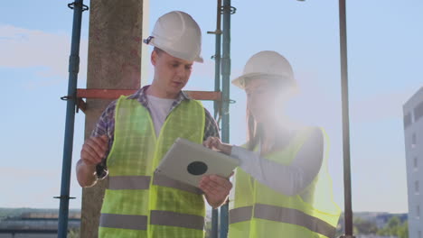 Construction-site-Team-or-architect-and-builder-or-worker-with-helmets-discuss-on-a-scaffold-construction-plan-or-blueprint-or-checklist